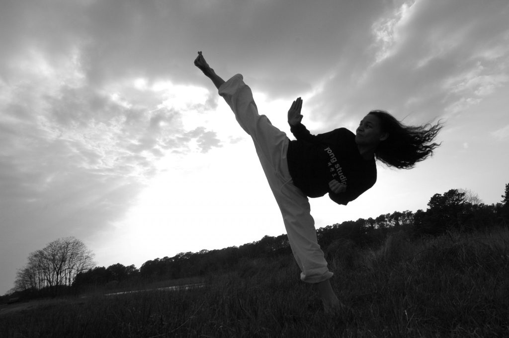 Image of a girl doing a side kick in nature